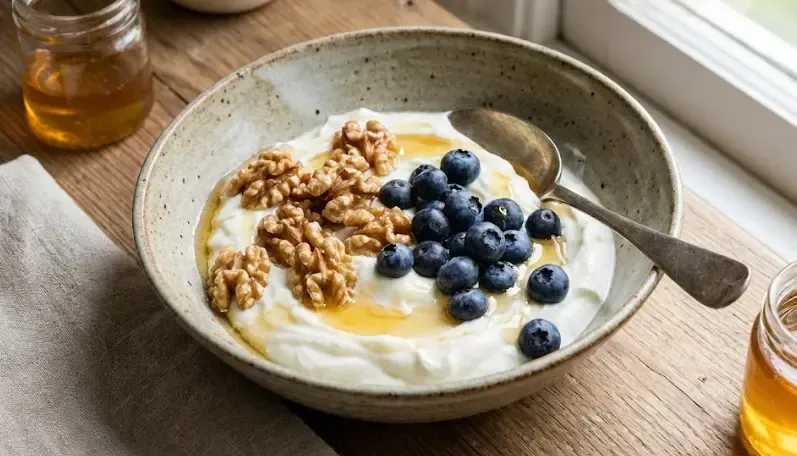 Bol con yogur griego, nueces, arándanos y un poco de miel, snack saludable